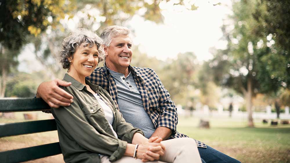 couple sitting on a bank and and he puts his hand on her shoulder