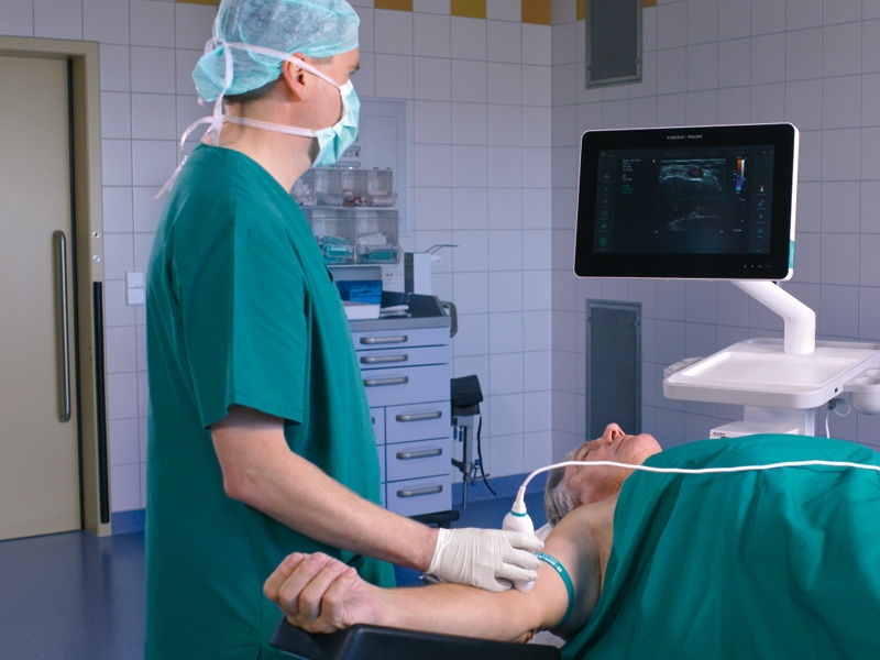 Placement of iv cannula using ultrasound done by medical doctor on lying patient 