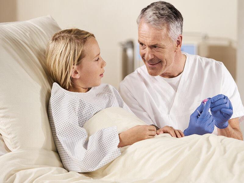 Pediatric nurse with boy at patient's bedside